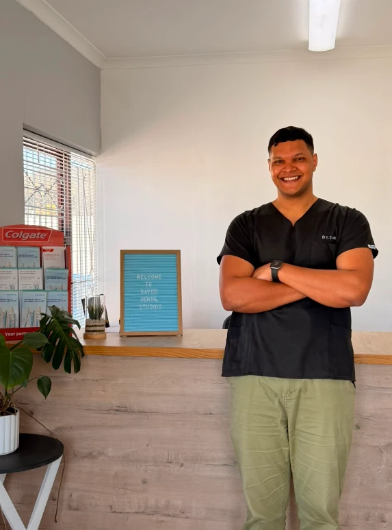 Dr E Davids at Davids Dental Studios, smiling at the reception desk